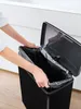 A person is putting a black trash bag into a black trash can. Produktbild-Vorschau