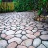 A garden path made of irregularly shaped stones with gravel in between, surrounded by greenery and a wooden fence. Náhľad obrázku produktu