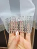 A hand is holding a sheer white curtain with a decorative silver trim made of small rhinestones. Produktbild-Vorschau