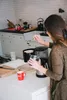 A woman is preparing coffee in a kitchen. Produktbild-Vorschau