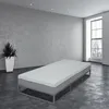 A mattress on a metal frame in a minimalist room with a large window. Produktbild-Vorschau