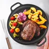 A cast iron pan filled with food, including steak, potatoes, and vegetables, is presented on a white surface. Voir les images du produit