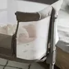 Close-up of a baby sleeping in a bedside crib, showing the mesh side and fabric details. Produktbild-Vorschau