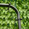A close-up of a black metal frame with a black net attached, set against a blurred green background of leaves. Náhled obrázku produktu