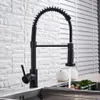 A black kitchen faucet with a pull-out spray head is shown in a kitchen sink. Náhľad obrázku produktu