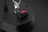 A close-up view of a black circular base with a red ON/OFF switch and a silver metal loop attached. Produktbild-Vorschau