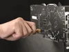 A hand is using a screwdriver to work on the back of a computer graphics card. Voir les images du produit