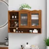 A wooden wall-mounted cabinet with glass doors, displaying various bathroom or cosmetic items. Produktbild-Vorschau