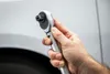 A hand holding a torque wrench in front of a car. Anteprima dell’immagine prodotto