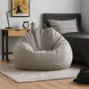 A bean bag chair is placed on a rug in a bedroom next to a desk and a bed. Voir les images du produit