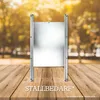 A metal chicken coop door is placed on a wooden surface with a blurred background of trees and foliage. Produktbild-Vorschau