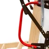 A close-up view of the mechanical components of a wooden attic ladder, including a red handle, metal springs, and brown metal supports. Produktbild-Vorschau