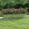 A raised garden bed filled with colorful flowers sits on a lawn in front of a lush green hedge. Náhled obrázku produktu