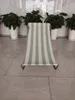 A striped beach chair is placed on a tiled floor in front of potted plants. Podgląd zdjęcia produktu