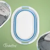 A top-down view of a collapsible laundry basket with clothes inside, set against a green background. Produktbild-Vorschau