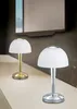 Two modern table lamps with white dome shades and metallic bases are displayed on a surface in front of a dark, textured wall and a large mirror. Produktbild-Vorschau