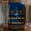 A wooden barrel-shaped wine cabinet with doors open, displaying bottles of Jack Daniel's whiskey and wine bottles, illuminated by blue LED lights. Produktbild-Vorschau