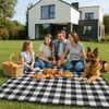 A family and their dog having a picnic on a checkered blanket in front of a modern house. Anteprima dell’immagine prodotto