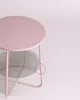 A small, round pastel pink side table with a woven basket underneath, against a light pink background. Náhled obrázku produktu