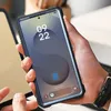 A person is holding a smartphone with a protective case. Produktbild-Vorschau