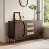 A dark wood sideboard with rattan drawer fronts and doors, decorated with framed pictures and a vase of greenery, placed in a room with a large window and a rug. Anteprima dell’immagine prodotto