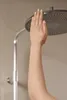 A hand touching a shower head. Produktbild-Vorschau