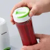 A hand is holding a sealed bottle with red liquid, next to a blender base. Podgląd zdjęcia produktu
