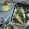 A close-up shot of a steaming dish of fish and spinach, with a grater and cheese in the background. Náhľad obrázku produktu