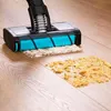 A vacuum cleaner head is shown cleaning up crumbs on a wooden floor. Náhled obrázku produktu