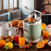 A breakfast scene with a citrus juicer, croissants, cookies, and fruit. Produktbild-Vorschau