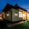 A house exterior at dusk with outdoor wall lights illuminated. Anteprima dell’immagine prodotto