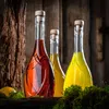 Three glass bottles filled with colored liquids, placed on a wooden surface with moss and a lemon in the foreground, against a rustic wooden background. Podgląd zdjęcia produktu