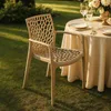A beige chair is placed on a grassy lawn next to a round table set for a meal. Produktbild-Vorschau