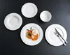 A top-down view of white plates and a bowl arranged on a black surface, with one plate containing a prepared meal. Produktbild-Vorschau