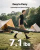 A man walks through a campsite carrying a long black bag, with tents in the background. Voir les images du produit