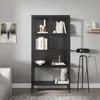 A black metal display cabinet with glass doors, filled with books and decorative items, is shown in a room setting with a grey wall and a floor rug. Náhľad obrázku produktu