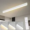 A long, white LED ceiling light fixture is shown mounted on a white ceiling. Below the main image, three smaller inset images show the light fixture at different color temperatures. A white remote control is also visible in the lower right corner. Náhled obrázku produktu