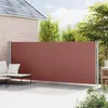 A retractable side awning is installed on a patio next to a brick house, with outdoor furniture visible. Náhled obrázku produktu