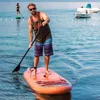 A man is paddleboarding on a body of water. Produktbild-Vorschau
