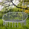 A gray macrame hammock chair with fringe hanging from a tree branch in a grassy outdoor setting. Náhľad obrázku produktu