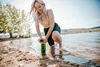 A woman is using a water purifier bottle by a lake. Produktbild-Vorschau