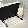 Close-up view of an open storage bench, showing the interior with folded white fabric and the hinge mechanism. Voir les images du produit