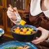 A person is eating fruit salad from a bowl with a fork. Náhled obrázku produktu