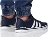 A close-up shot of a person's feet wearing dark blue Adidas sneakers and denim jeans. Náhľad obrázku produktu