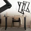 A dining table with black X-shaped legs, a chair with a woven seat, and a rug. Náhľad obrázku produktu