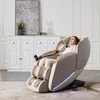 A woman is relaxing in a beige massage chair in a well-lit room with white furniture in the background. Produktbild-Vorschau