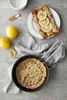 A frying pan with a pancake and rolled crepes with lemon slices on a grey surface, with lemons and a salt spoon nearby. Podgląd zdjęcia produktu