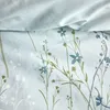 A close-up view of a light blue duvet cover with a floral pattern of green and white flowers and stems. Produktbild-Vorschau
