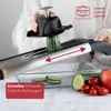 A person is using a mandoline slicer to cut a cucumber over a glass dish. Sliced cucumbers, cherry tomatoes, and an apple are visible. Produktbild-Vorschau