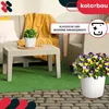 An outdoor patio setting with wicker furniture, a coffee table with a potted plant, and a larger pot of pansies in the foreground. Produktbild-Vorschau